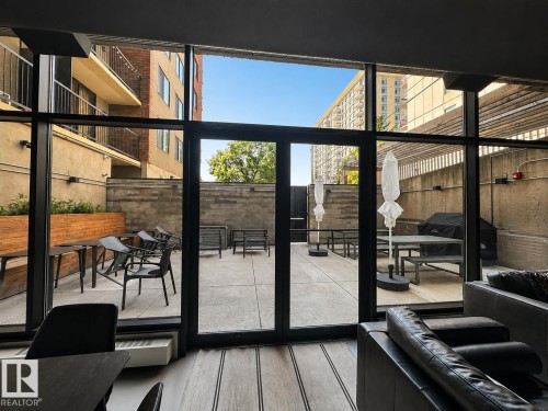 Expansive outdoor patio area featuring a concrete surface, perimeter concrete walls, and wood paneling accents - #301 9808 103 St Nw, Edmonton, AB - 