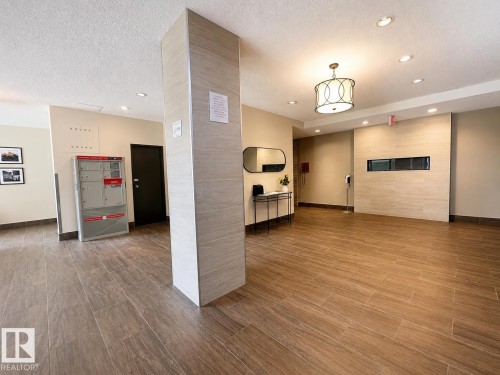 Spacious common area featuring wood-look tile flooring, a built-in linear fireplace, recessed lighting, and a decorative chandelier - #301 9808 103 St Nw, Edmonton, AB - Indoor Photo Showing Other Room