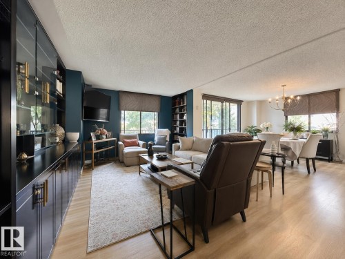 Open-concept living and dining area featuring wood-finish flooring, recessed lighting, and large windows with blinds - #301 9808 103 St Nw, Edmonton, AB - Indoor