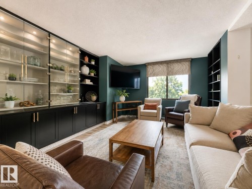 Built-in cabinetry with glass-front uppers and lower storage, complemented by recessed lighting - #301 9808 103 St Nw, Edmonton, AB - Indoor Photo Showing Living Room