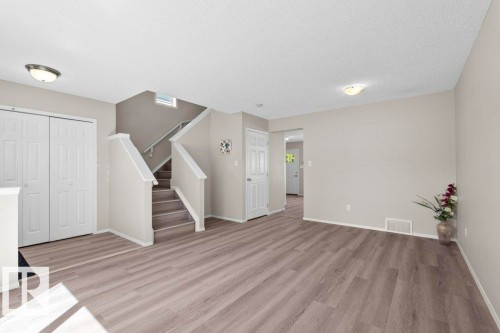 Spacious interior featuring wood-finish flooring, neutral wall tones, and a staircase with light carpeted treads - 21344 88 Avenue Nw, Edmonton, AB - Indoor Photo Showing Other Room