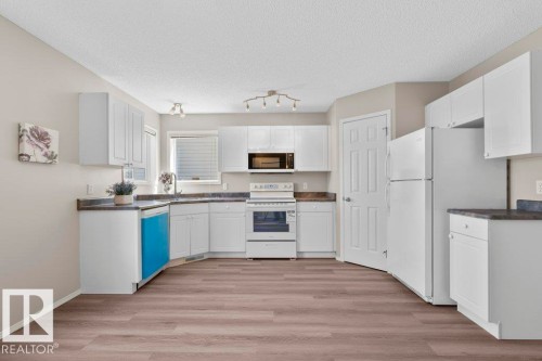 U-shaped kitchen featuring white cabinetry, dark countertops, and wood-finish flooring - 21344 88 Avenue Nw, Edmonton, AB - Indoor Photo Showing Kitchen