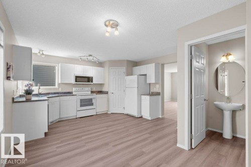 Kitchen featuring white cabinetry, white appliances, dark countertops, and wood-finish flooring - 21344 88 Avenue Nw, Edmonton, AB - Indoor Photo Showing Kitchen
