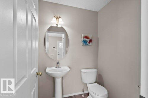Pedestal sink with an oval mirror and two-light vanity fixture - 21344 88 Avenue Nw, Edmonton, AB - Indoor Photo Showing Bathroom