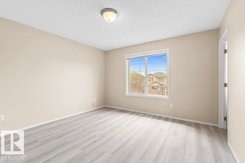 Room featuring wood-finish flooring, neutral wall tones, white trim, and a window with grid patterns - 21344 88 Avenue Nw, Edmonton, AB - Indoor Photo Showing Other Room