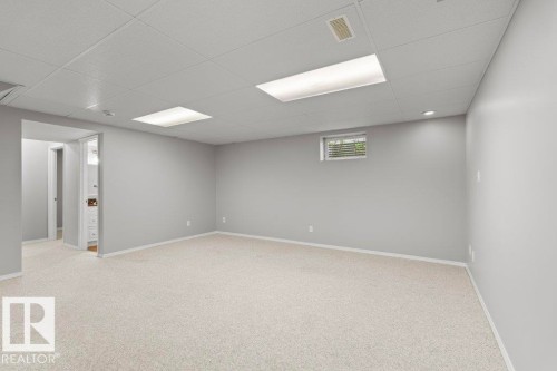Spacious room featuring light-colored carpeting, neutral painted walls, and a drop ceiling with recessed lighting - 21344 88 Avenue Nw, Edmonton, AB - Indoor Photo Showing Basement