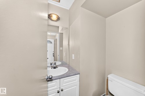 Vanity with an integrated sink, dual-handle faucet, white cabinetry, and a full-width mirror - 6416 180 Street Nw, Edmonton, AB 