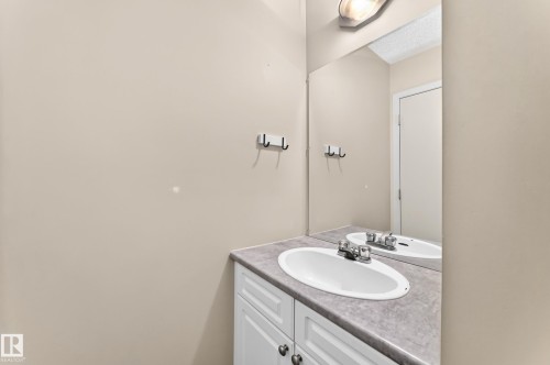 White vanity with paneled doors, oval undermount sink, and a gray countertop - 6416 180 Street Nw, Edmonton, AB 