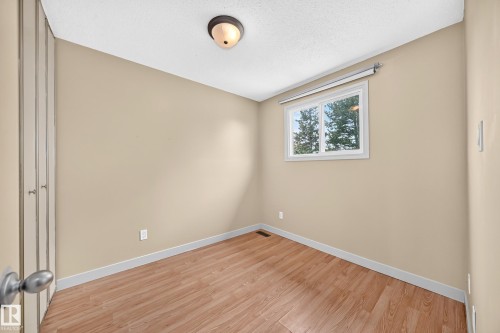 Wood-finish flooring, single window with white trim, flush mount ceiling light, and bi-fold closet doors - 6416 180 Street Nw, Edmonton, AB 