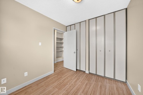 Wood-finish flooring with a neutral wall color, bi-fold closet doors, and recessed shelving - 6416 180 Street Nw, Edmonton, AB 