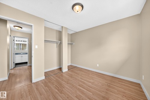 Wood-finish flooring, recessed wardrobe space with shelving, and a flush mount ceiling light - 6416 180 Street Nw, Edmonton, AB 