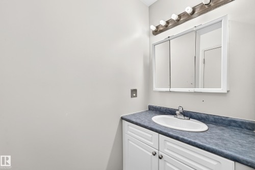 White vanity with cabinet storage, integrated sink, and vanity lighting - 6416 180 Street Nw, Edmonton, AB 