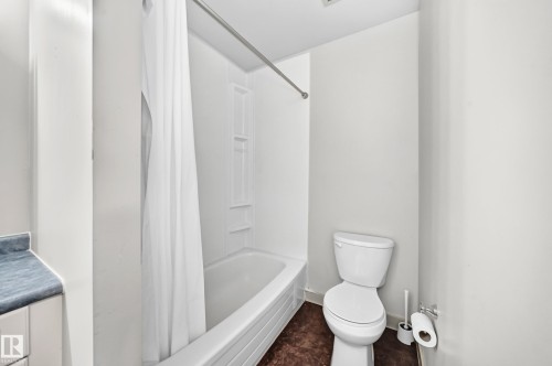 White bathtub with integrated shower, white toilet, and a built-in vanity with a blue countertop - 6416 180 Street Nw, Edmonton, AB 