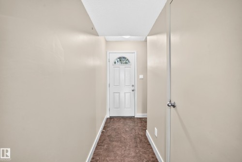 Entryway featuring a white paneled door with an arched glass insert, light-toned walls, and dark-toned flooring - 6416 180 Street Nw, Edmonton, AB 
