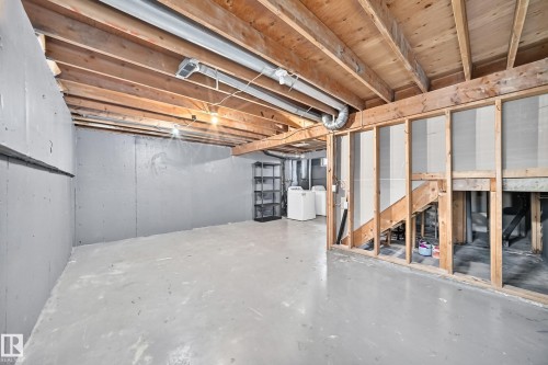 Unfinished basement with exposed wood joists, concrete flooring, and laundry appliances - 6416 180 Street Nw, Edmonton, AB 