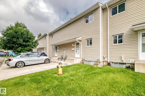 Siding exterior with multiple windows, concrete walkway, and a landscaped lawn - 6416 180 Street Nw, Edmonton, AB 