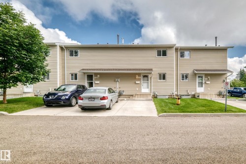 Multi-unit exterior with beige siding, white trim windows, and individual paved driveways - 6416 180 Street Nw, Edmonton, AB 