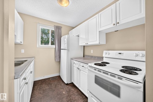 White cabinetry, built-in sink, freestanding electric range, and a refrigerator - 6416 180 Street Nw, Edmonton, AB 