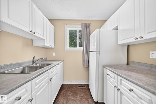 White cabinetry, stainless steel double basin sink, neutral countertops, and a window - 6416 180 Street Nw, Edmonton, AB 