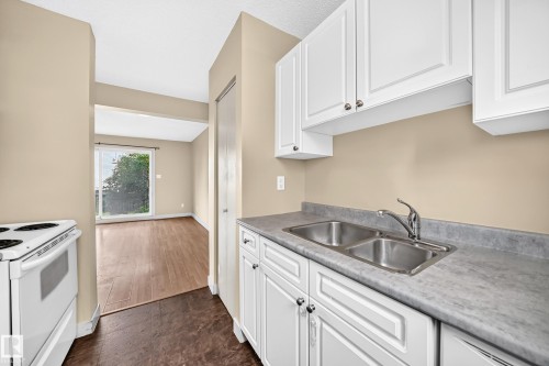 Kitchen featuring white cabinetry, a double basin stainless steel sink, and light gray countertops - 6416 180 Street Nw, Edmonton, AB 