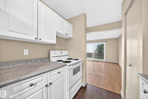 Kitchen featuring white cabinetry with silver-tone hardware, a white electric range, and gray countertops - 6416 180 Street Nw, Edmonton, AB 