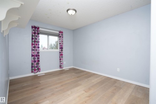Wood-finish flooring with white trim - 1009 Macewan Close Sw, Edmonton, AB - Indoor Photo Showing Other Room