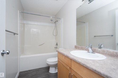 Wood-finish vanity with an integrated sink and chrome faucet, set against a full-width mirror - 1009 Macewan Close Sw, Edmonton, AB - Indoor Photo Showing Bathroom