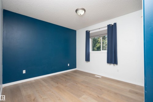 Wood-finish flooring, accent wall, and a flush mount ceiling light - 1009 Macewan Close Sw, Edmonton, AB - Indoor Photo Showing Other Room