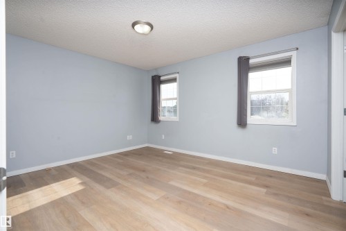 Wood-finish flooring, two windows with white trim, and a ceiling-mounted light fixture - 1009 Macewan Close Sw, Edmonton, AB - Indoor Photo Showing Other Room