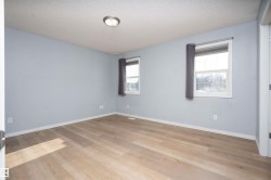 Wood-finish flooring, two windows with white trim, and a ceiling-mounted light fixture - 