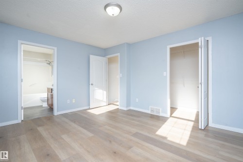 Light wood-finish flooring, light blue wall paint, white trim, and a ceiling-mounted light fixture - 1009 Macewan Close Sw, Edmonton, AB - Indoor Photo Showing Other Room