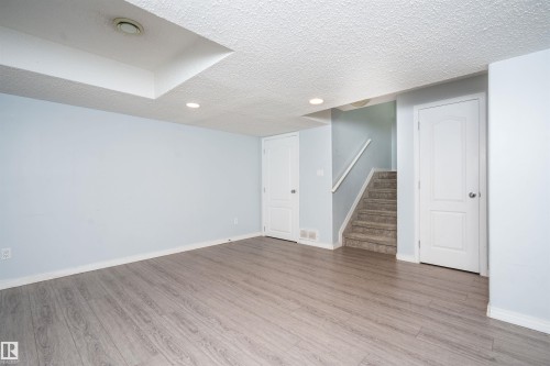 Wood-finish flooring, recessed ceiling lighting, two panel doors, and carpeted stairs with a white handrail - 1009 Macewan Close Sw, Edmonton, AB - Indoor Photo Showing Other Room