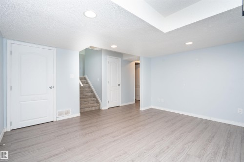 Recessed lighting, light wood-finish flooring, textured ceiling, white interior doors, and a carpeted staircase - 1009 Macewan Close Sw, Edmonton, AB - Indoor Photo Showing Other Room