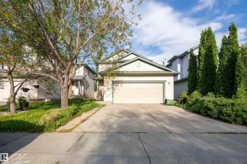 Exterior featuring an attached garage, a paved driveway, and established front landscaping - 1009 Macewan Close Sw, Edmonton, AB - Outdoor With Facade