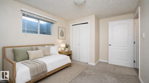 Neutral paint palette, carpeted flooring, window with blinds, bi-fold closet doors, and panel-style interior door - 1009 Macewan Close Sw, Edmonton, AB - Indoor Photo Showing Other Room