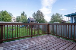 Wood-finish deck with railing overlooking a fenced yard - 