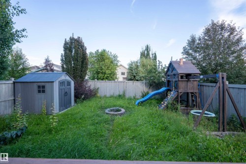 Fenced backyard featuring a storage shed, a fire pit, and mature trees - 1009 Macewan Close Sw, Edmonton, AB - Outdoor With Backyard