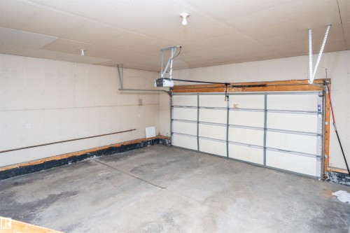 Concrete flooring, overhead garage door, built-in garage door opener, ceiling-mounted lighting - 1009 Macewan Close Sw, Edmonton, AB - Indoor Photo Showing Garage