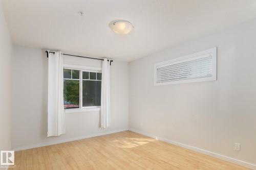 Light wood-finish flooring, white walls, and a multi-pane window - #110 9523 160 Av Nw, Edmonton, AB - Indoor Photo Showing Other Room