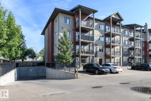 Multi-story building featuring balconies, stone accents, and a subterranean parking entrance - #110 9523 160 Av Nw, Edmonton, AB - Outdoor With Balcony With Facade