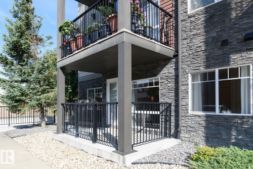 Stacked stone exterior with white window frames - #110 9523 160 Av Nw, Edmonton, AB - Outdoor With Balcony