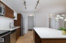 Kitchen featuring wood-finish cabinetry, stainless steel appliances, white countertops, and track lighting - #110 9523 160 Av Nw, Edmonton, AB 