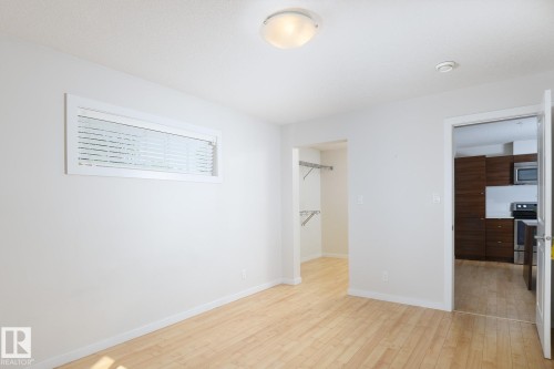 Light wood-finish flooring, white walls, and a flush mount ceiling light - #110 9523 160 Av Nw, Edmonton, AB - Indoor Photo Showing Other Room