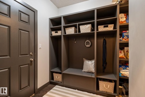 Built-in shelving unit with an integrated bench, dark paneled door, and wood-finish flooring - 1337 Secord Landing Nw, Edmonton, AB - Indoor