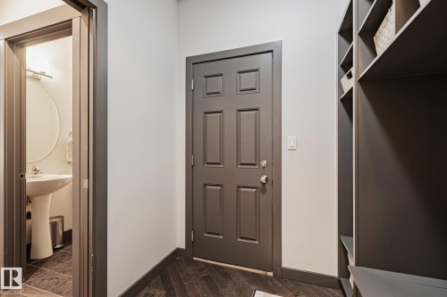 Entryway featuring a paneled door, built-in shelving, and wood-finish flooring - 1337 Secord Landing Nw, Edmonton, AB - Indoor