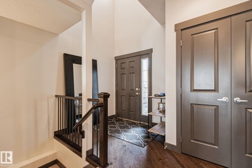 Vaulted entryway with wood-finish flooring, dark wood newel post, and paneled doors - 1337 Secord Landing Nw, Edmonton, AB - Indoor Photo Showing Other Room