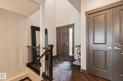 Vaulted entryway with wood-finish flooring, dark wood newel post, and paneled doors - 