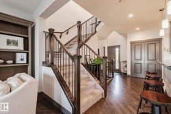 Hardwood-finish flooring, built-in shelving, carpeted staircase with wood newel posts, iron balusters, and a paneled entry door - 