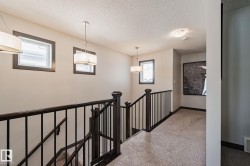 Staircase featuring dark wood newel posts and railings with black metal balusters, complemented by a light-toned carpeted landing and recessed lighting - 
