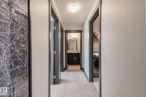 Hallway featuring carpet flooring, multiple doorways, and a flush mount ceiling light - 1337 Secord Landing Nw, Edmonton, AB - Indoor